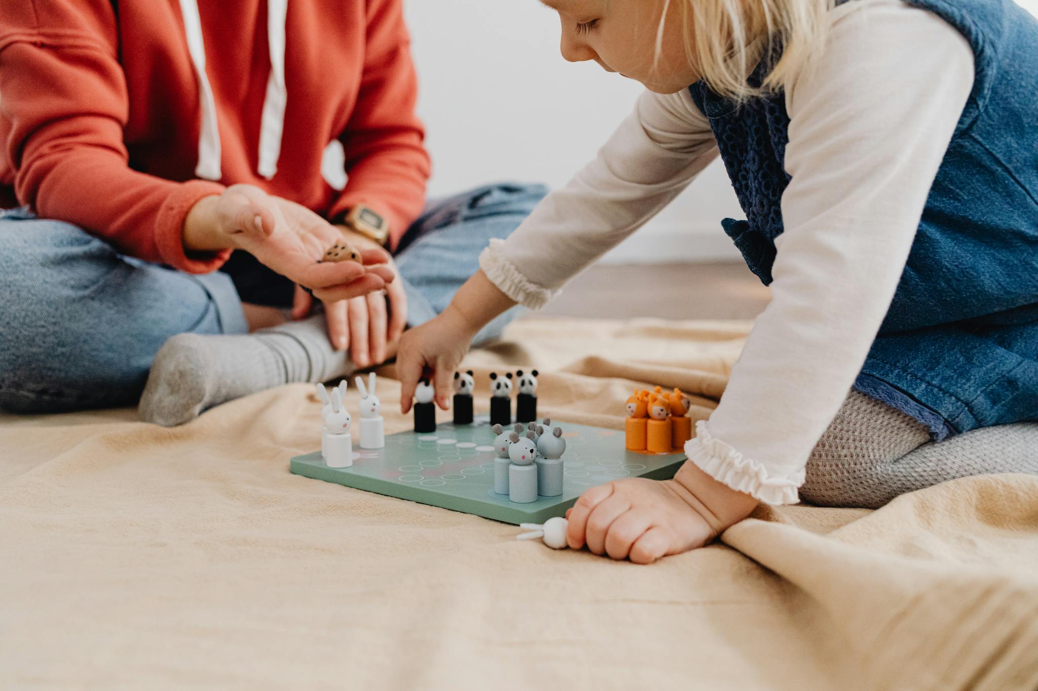 A child and adult enjoy a fun board game with animal tokens indoors, fostering creativity and playfulness.
