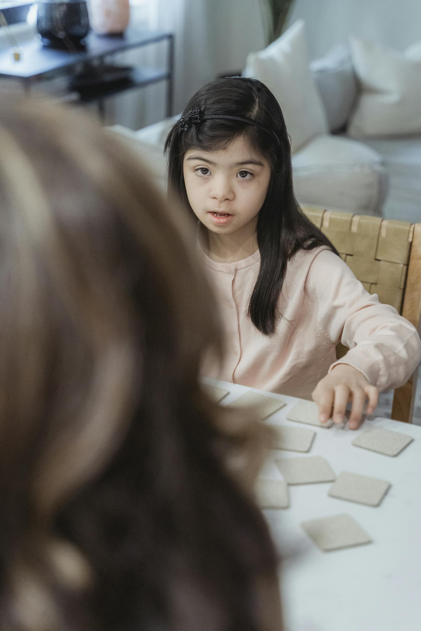 A young girl focuses intently while playing a card game indoors at home.