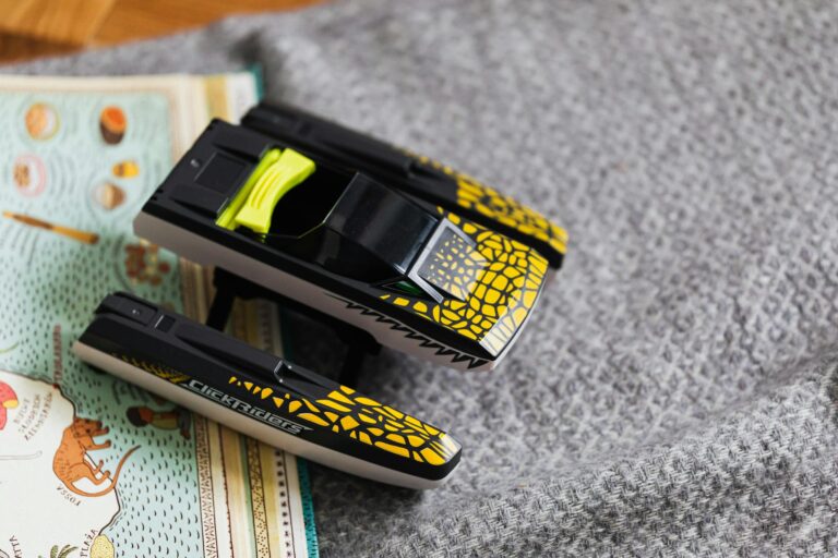 Close-up of a toy car with a vibrant design placed on a textured blanket next to a map.