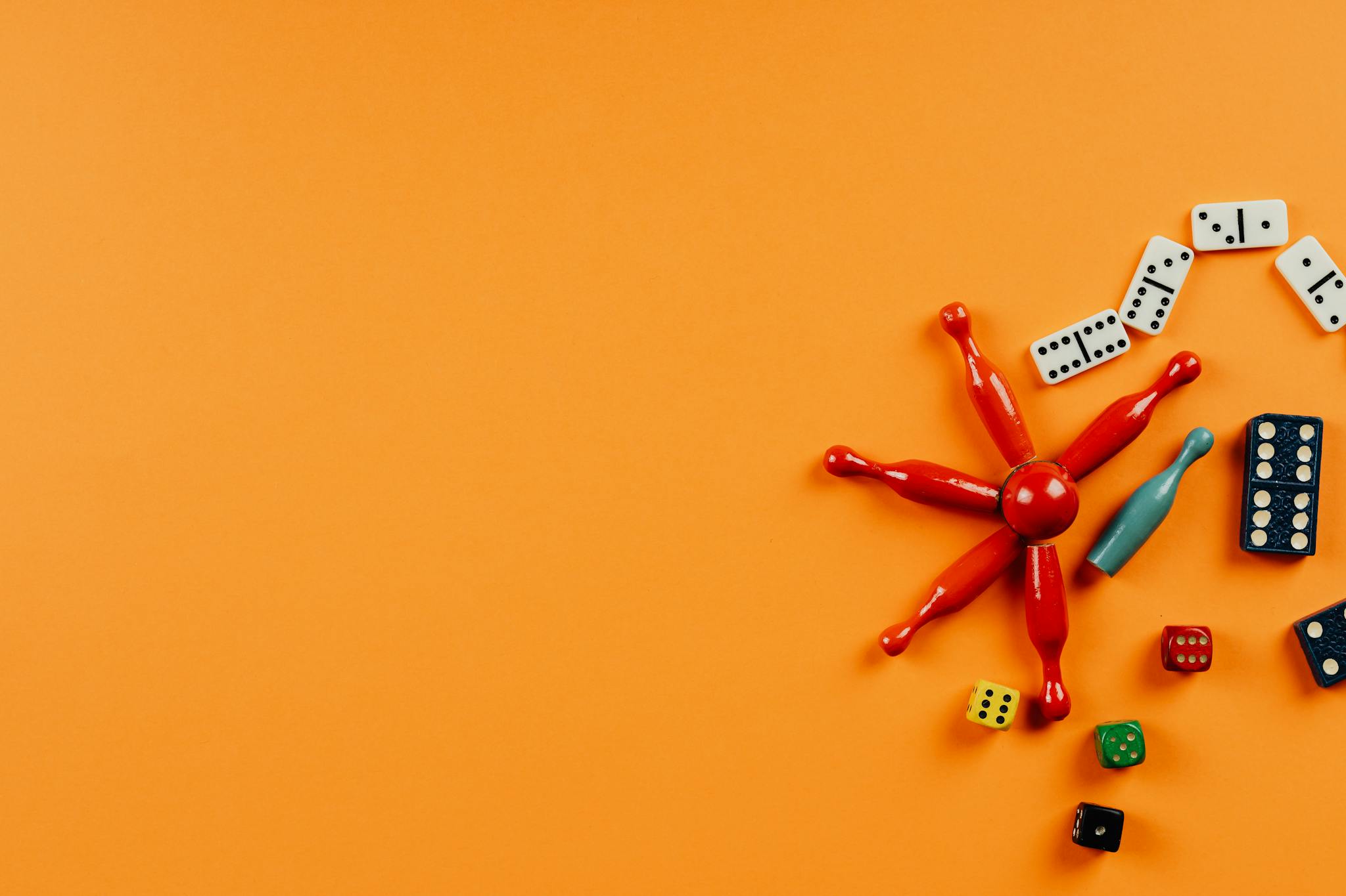 Colorful toys including dominoes and pins arranged on a vibrant orange background.