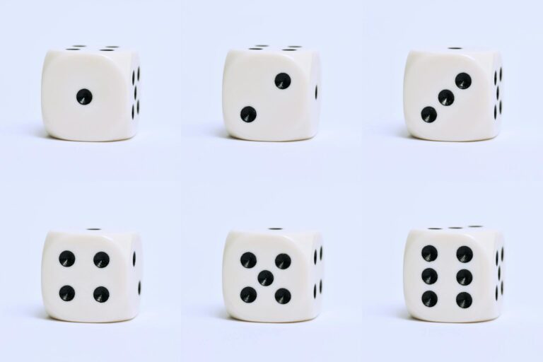 Detailed close-up of six white dice on a plain surface, focusing on different numbers.